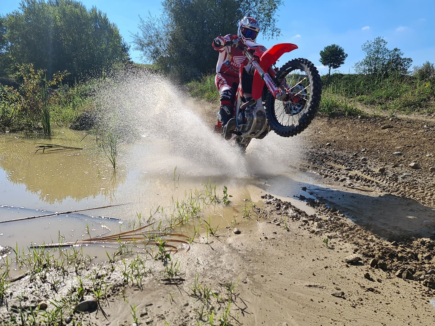 Enduro Training mit dem eigenen Motorrad: Fahrer fährt durch einen Bach, das Wasser spritzt