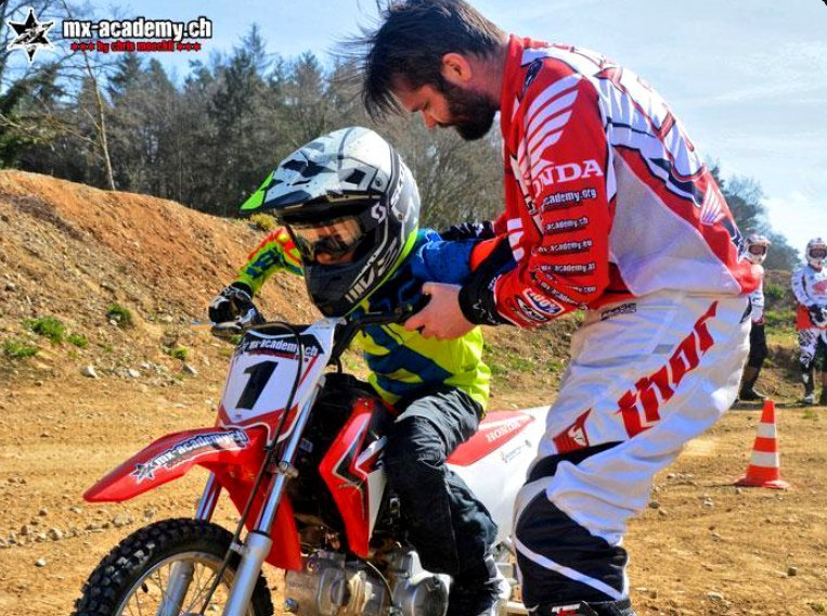 Motocross Schnupperkurs für kleine Kinder: Trainer hält ein Kind mit Startnummer 1 auf dem Bike